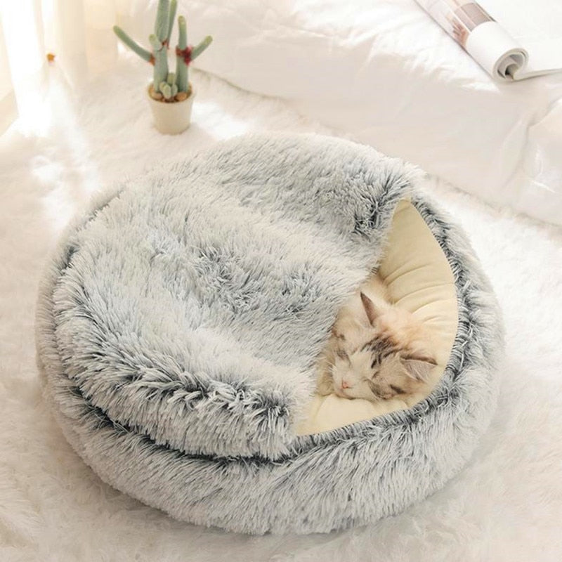 Fluffy gray pet bed with a cat inside on a soft white surface.