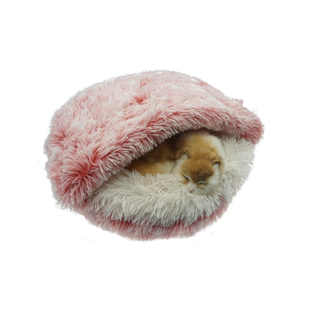 Fluffy pink and white pet bed with a cat inside on a white background