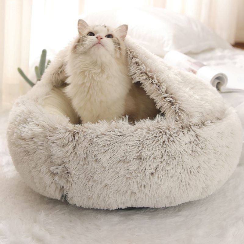Cat sitting inside a fluffy white pet bed on a light-colored surface.